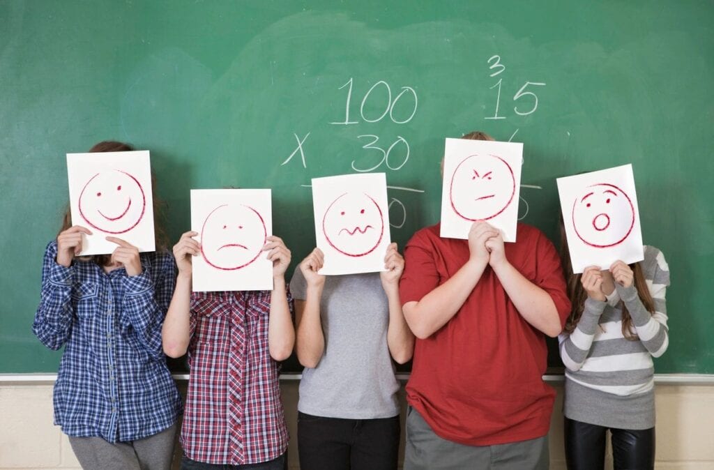 Students holding paper with smiley faces and frowns